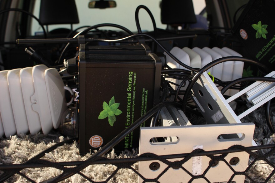 A black box with a green logo lays on its side in the back of an SUV.