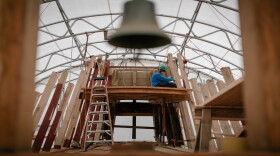 A Mystic Seaport Museum shipwright works on Mayflower's restoration, seen through the ship's belfry.