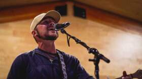 Long-angle shot of a man in a white ball cap singing into a microphone