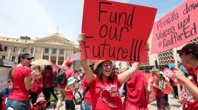An Arizona teacher holds up a sign in front of the State Capitol during a #REDforED rally on April 26, 2018 in Phoenix, Ariz. Teachers statewide staged a walkout strike on Thursday in support of better wages and state funding for public schools. (Ralph Freso/Getty Images)