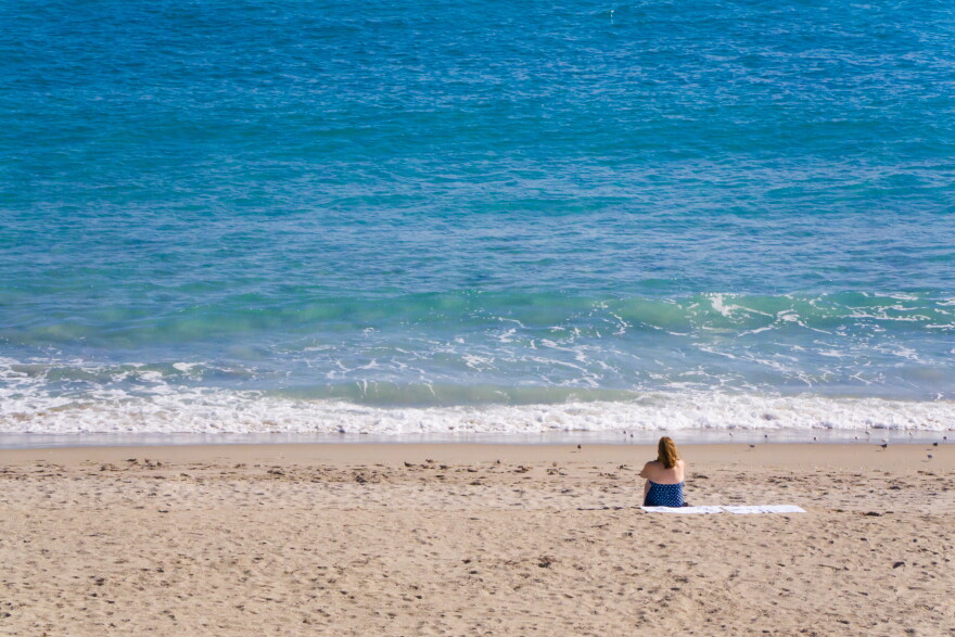 A woman sits on the beach in Stuart, Florida on a sunny Summer morning