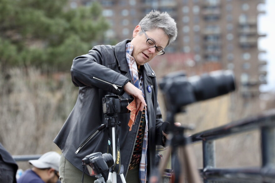 Michelle Roffman, an Earth science teacher from Penfield, says, “I’ve never done this but I’m going to try” as she wipes the lens clean while setting up on the High Falls overlook.