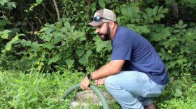 Garrett Betts checks the water level on his 1,000-gallon, buried water storage tank. The Betts have to keep close tabs on how much water they use for dishes and laundry, occasionally making the trek to check on the tank.