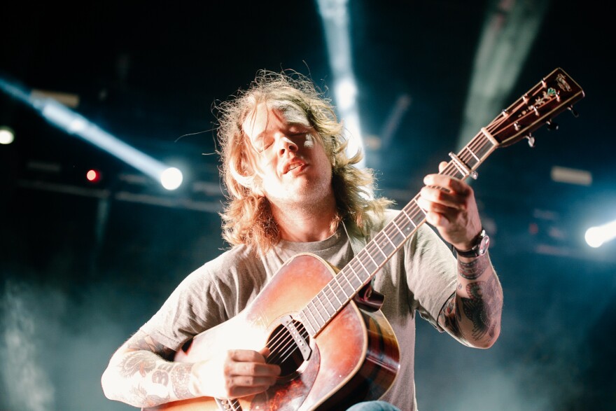 Billy Strings leans over the crowd while playing guitar at Hinterland music festival 2022. 