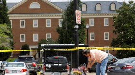 A resident places flowers at a memorial the day after the shootings deaths of 12 people in Virginia Beach, Va.
