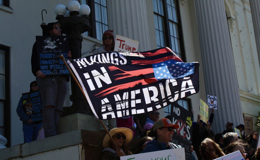 Protestor waving a flag stating "No Kings in America" outside of Thalian Hall in downtown Wilmington.