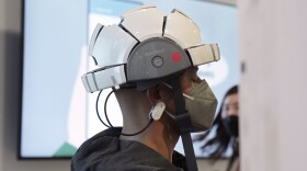 A persons wears the iSyncWave EEG brain mapping and LED therapy device at the iMediSync booth during the CES tech show Thursday, Jan. 6, 2022, in Las Vegas. 