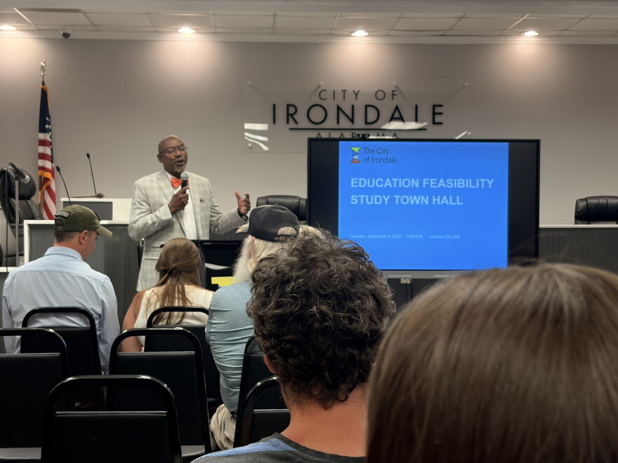 Irondale Mayor James Stewart speaks to an audience and stands beside a screen that reads "Education Feasibility Study Town Hall."