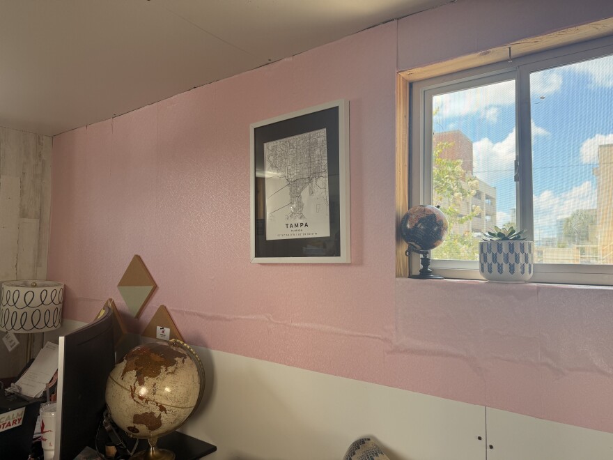A wall that is half pink and half white with a window and a picture of a black and white map of Tampa