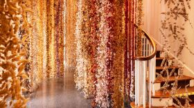 Rows of dried flowers hang from ceiling. A bansiter and staircase appear on the right of frame.
