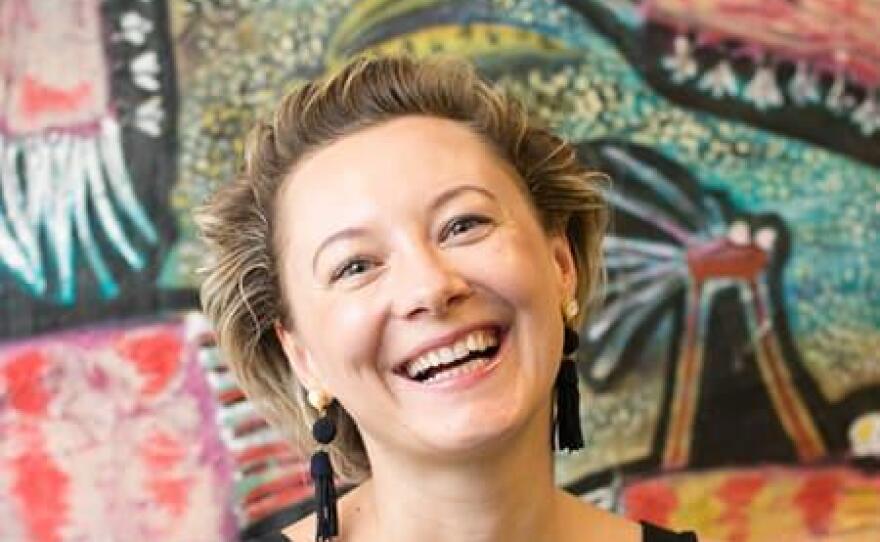 Belarus poet Valzhyna Mort poses in front of a colorful painting, with a smile on her face.