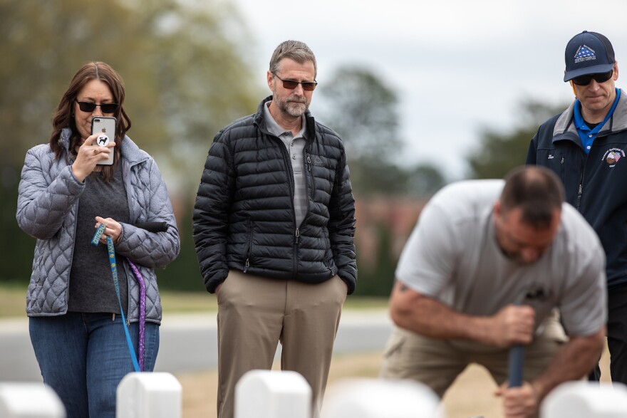 Ivar Lonon, middle, and his wife Paige Lonon, left, watch as a worker at Salisbury National Cemetery buries the remains of Ivar's father and mother in Salisbury, N.C., on Thursday, March 26, 2020. 