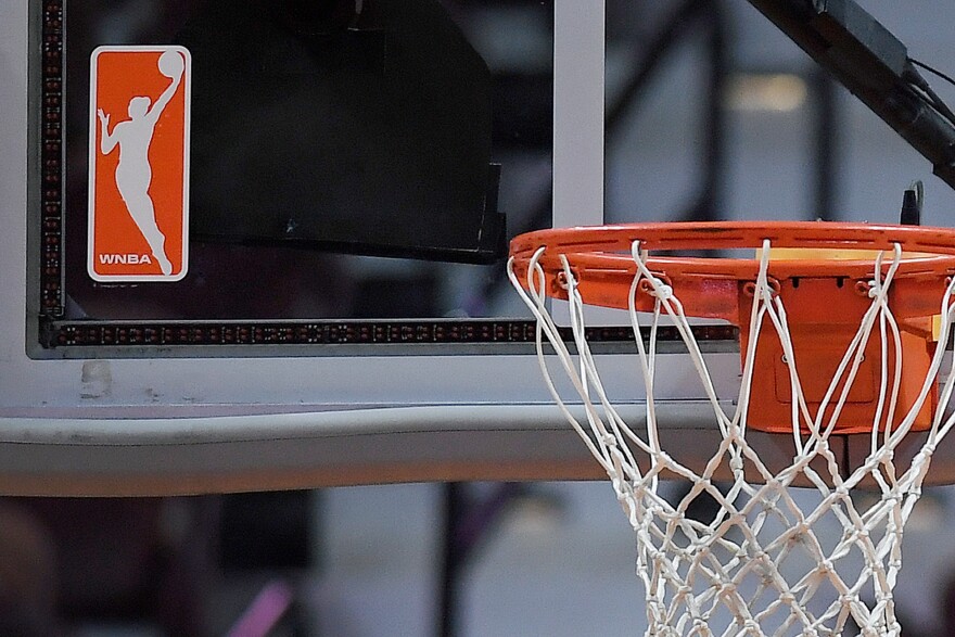 FILE - The WNBA logo is seen near a hoop before an WNBA basketball game at Mohegan Sun Arena, May 14, 2019, in Uncasville, Conn. (AP Photo/Jessica Hill, File)
