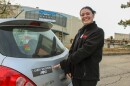 JOLT Harm Reduction's Nakota Facker stands next to the trunk of her car. She's pointing to a sticker on it that reads "I carry naloxone" followed by "JOLT," referring to the harm reduction organization. 