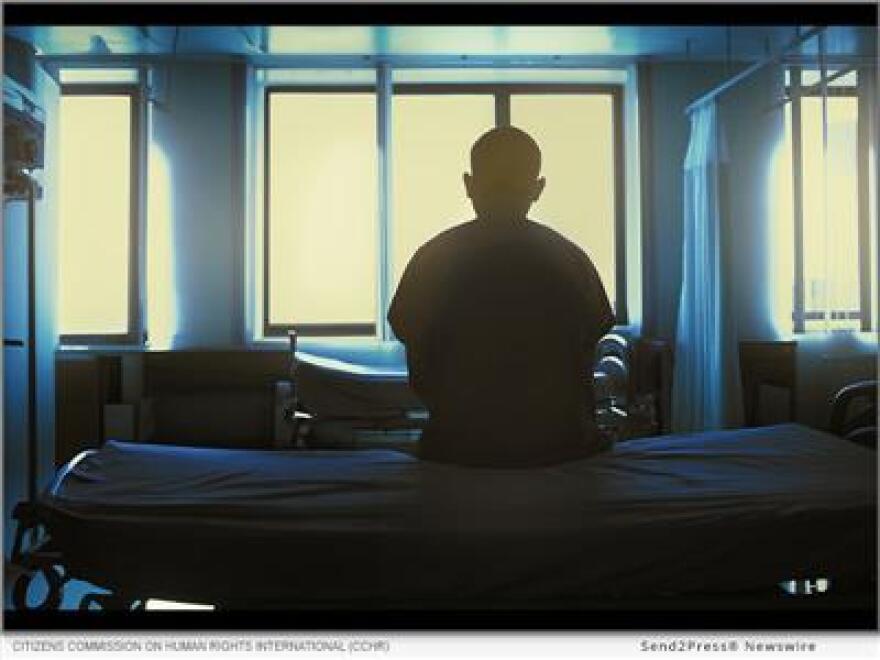 A person sits alone in a dark room.