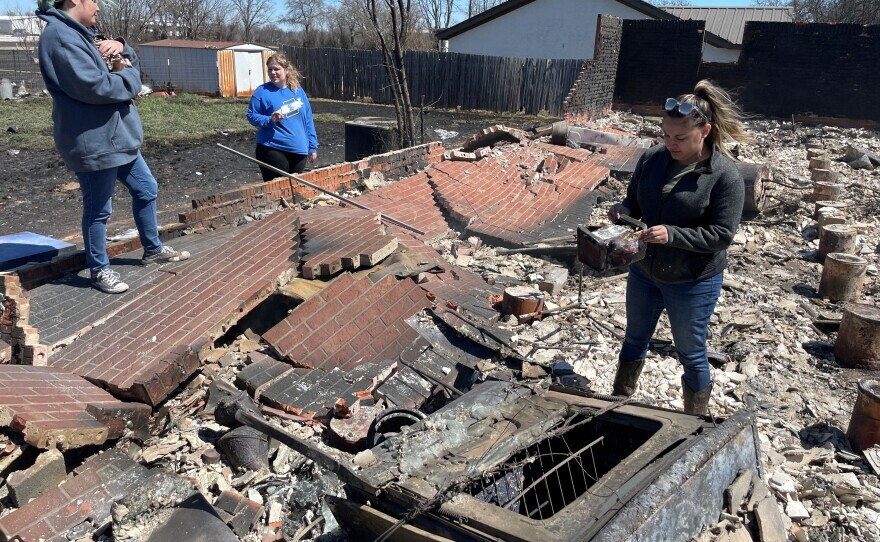 Abby Felchner, Bre Riggs and Priscilla Maynard go through the debris of a friend's house which burned in the Eastland Complex wildfire in Eastland County, Texas, U.S. March 18, 2022.