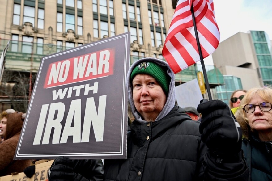 A protester holds a sign opposing the Iran war as thousands of people march through Portland, Maine, as part of the No Kings protest on Saturday, March 28, 2026. (Photo by Jim Neuger/Maine Morning Star)