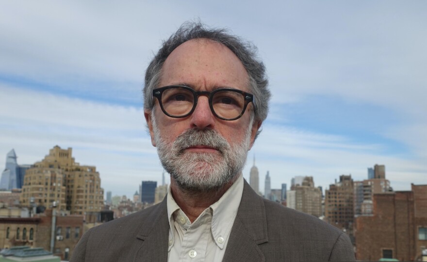 A color image of Michael Azerrad with a city skyline behind him. 