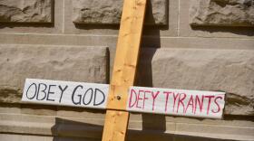 A cross carried at a protest on the lawn of the Indiana Statehouse in opposition to vaccination requirements from government.