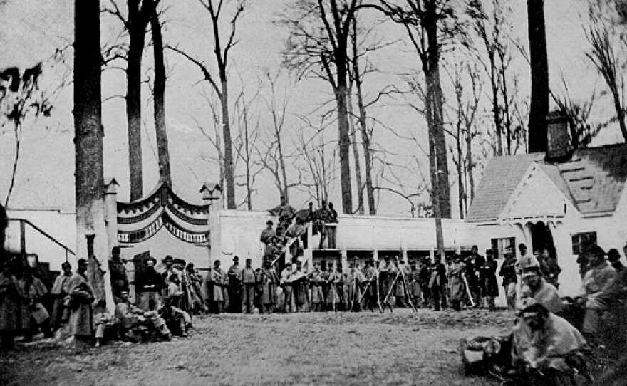A black-and-white Civil War-era photograph showing the guard house and entrance of Camp Morton in Indiana, with several union soldiers standing guard in a row.