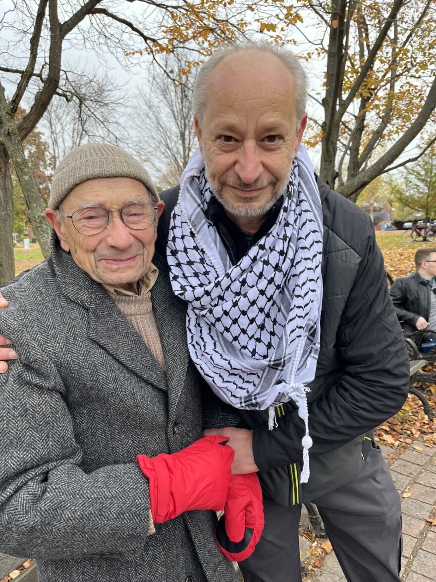 Two men in winter clothes pose for the camera outside.
