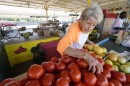 Brenda Langham, has three fans blowing in her direction as she arranges the home-grown tomato display at Brenda's Produce, a farmer's market outdoor store owned and operated by her family for over 50 years, in Jackson, Miss., Wednesday, June 28, 2023.