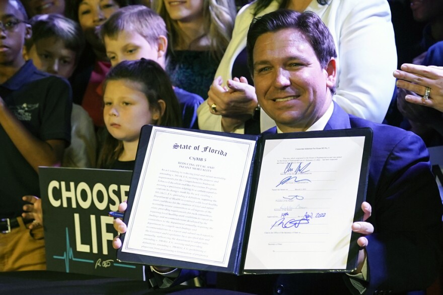 Florida Gov. Ron DeSantis holds up a 15-week abortion ban law after signing it on April 14, 2022, in Kissimmee. Florida later imposed a six-week ban. (AP Photo/John Raoux, File)