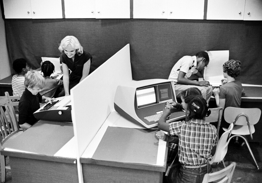 FILE - Nancy Armstrong, a teacher at the Marshall Elementary School in Harrisburg, Penn., assists her students in the use of computers to aid them in their studies. Friday, May 17, 2024, marks 70 years since the U.S. Supreme Court ruled that separating children in schools by race was unconstitutional. On paper, Brown v. Board of Education still stands. In reality, school integration is all but gone, the victim of a gradual series of court cases that slowly eroded it, leaving little behind. (AP Photo/Paul Vathis, File)
