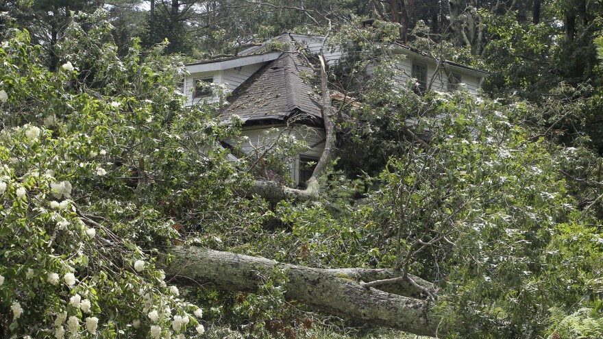 A house sits damaged by a fallen tree in South Kingstown, R.I., on Monday. Strong winds from Tropical Storm Henri downed trees and power lines across the state, leaving residents without power.