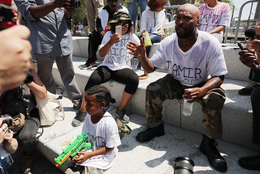 Crawford, joined by his daughter, speaks out against the shooting of 12 year-old Tamir Rice near the site of the Republican National Convention in downtown Cleveland.