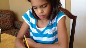 Fourth grader Isa Ruegger completes a page in her workbook at home.