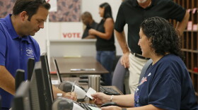 Summerlinn Muhammad, right, elections assistant, checks in Jason Soper, right, for early voting in Oklahoma City, Thursday, Aug. 18, 2016. 