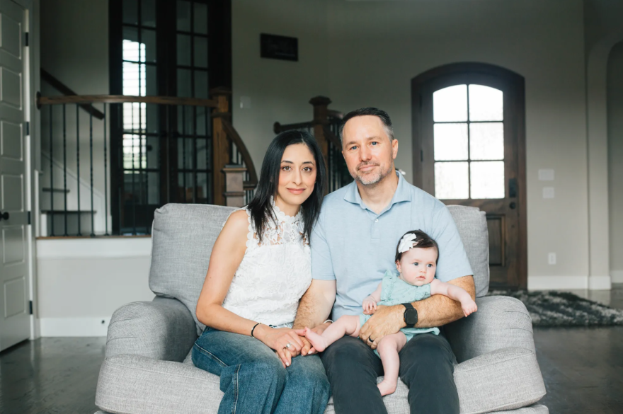 Parents Kevin Stone and Angie Koriakos sit with daughter Eliana Stone in their home in Dallas on Aug. 26, 2026. Eliana was born via a surrogate.