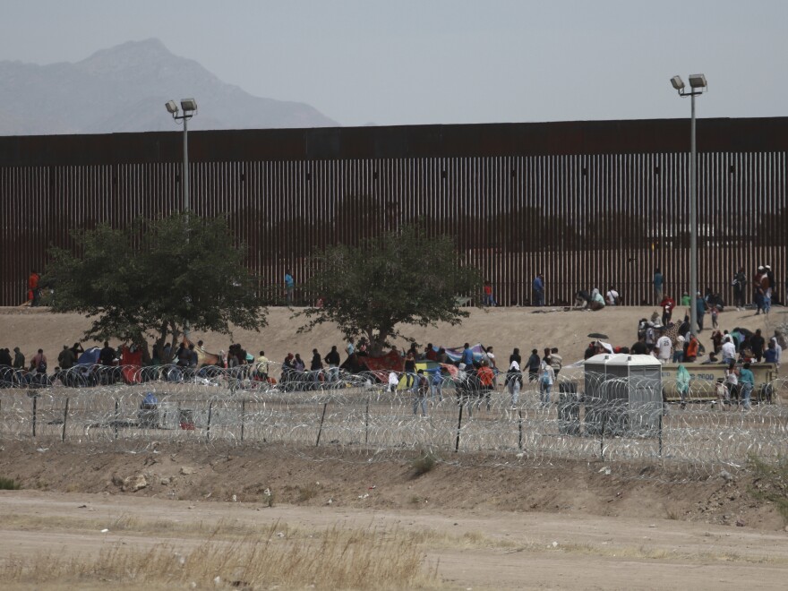 Migrants camp out between a barbed-wire barrier and the border fence between El Paso, Texas, and Ciudad Juárez, Mexico. Thousands are expected to seeks asylum when pandemic restrictions this week.