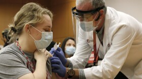 Ohio State employee Lauren Chisholm, left, receives a Pfizer-BioNTech COVID-19 vaccination from Robert Weber Monday, Dec. 14, 2020, in Columbus.