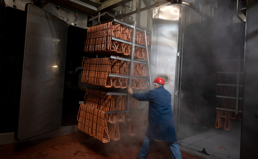 A worker moves a trolley of hot dogs along a rail system on the ceiling from the smoker where they were cooked into the cooling room at the Hummel Bros. hot dog factory in New Haven on June 22, 2021, ahead of the 4th of July holiday.