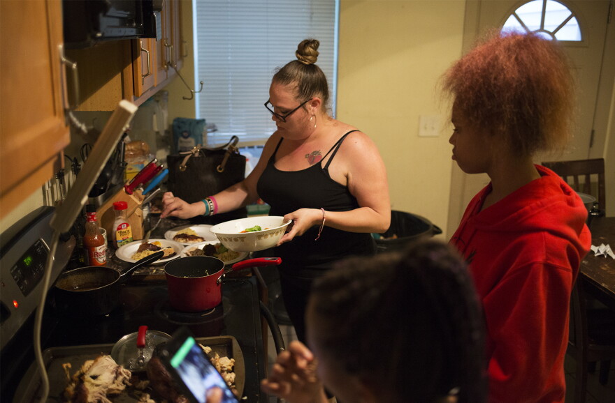 Regina Hartfield serves dinner for her children in their south St. Louis home. The state's Medicaid dropped her children from the program in late summer. 