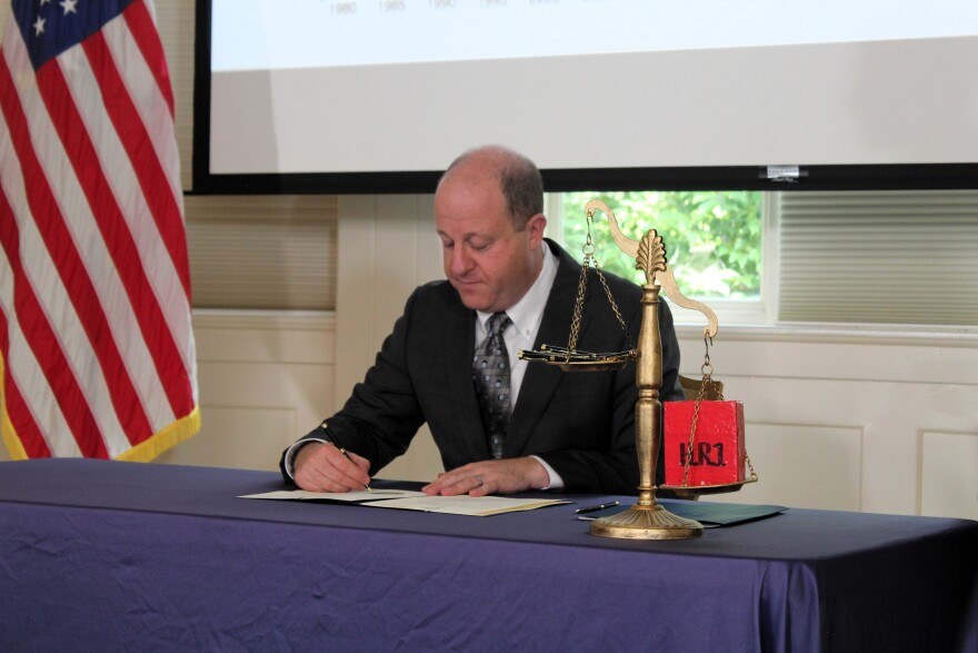 Colorado Gov. Jared Polis signs off on cuts to the state budget to plug a roughly $750 million hole in the state budget caused by the One Big, Beautiful Bill Act on Aug. 28, 2025, at the governor's mansion in downtown Denver.