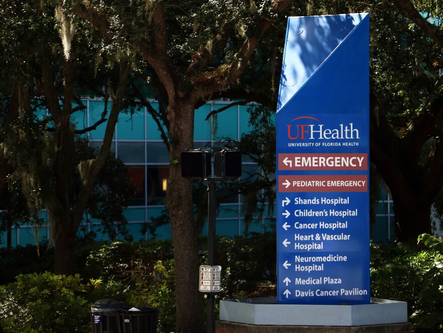 UF Health Hospital in Gainesville, Fla. Blue sign outside with trees in background. 