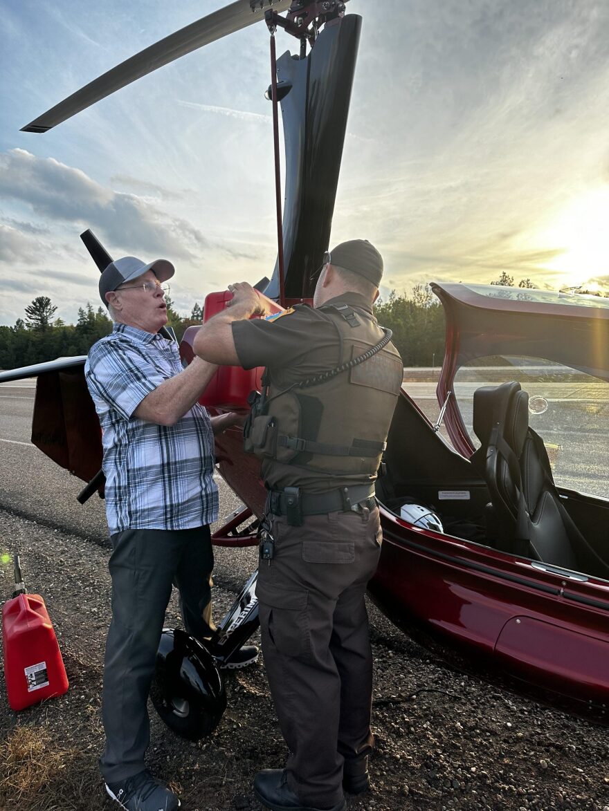 A Lincoln County Deputy helps a helicopter pilot refuel after an emergency landing on US 51.