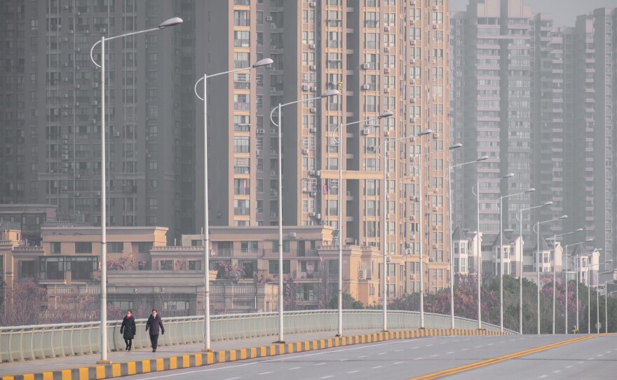 People walk down a deserted street in Wuhan, epicenter of the coronavirus outbreak, on Tuesday. Wuhan has gradually shut down all transportation channels for entering and leaving the city — no flights, trains, buses or boats.