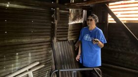a woman in a blue shirt stands in an empty smokehouse