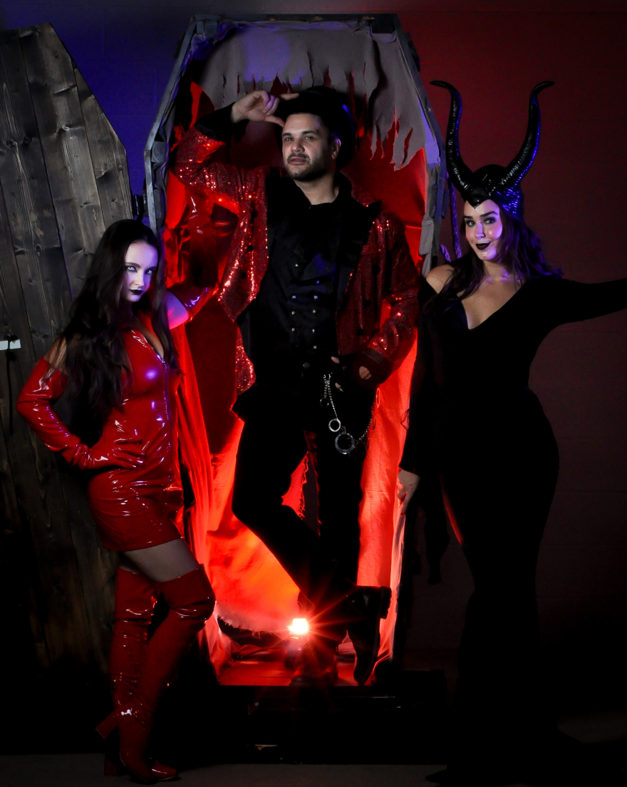 Connor Bogart O'Brien stands in a coffin with two costumed Halloween performers