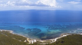 An aerial view of Mahahual shows the close relationship between the Caribbean Sea, coastal mangroves, and the Mesoamerican Reef System. The landscape highlights the fragile balance between marine and terrestrial ecosystems that defines the region.