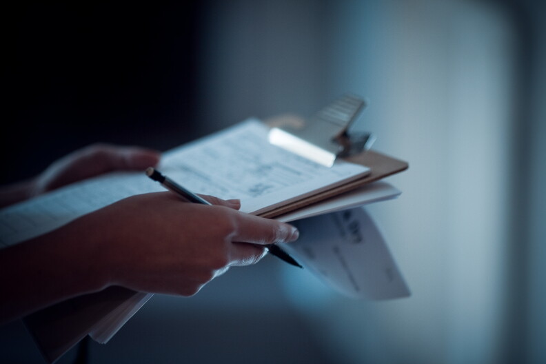 A person holds a clipboard and papers.