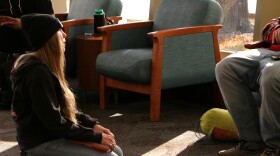 Dr. Mo with Midwest Street Medicine kneels to talk with a man in the Siouxland Downtown Library in Sioux Falls, S.D., on Nov. 17, 2025.