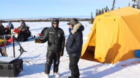 a musher talks to another man outside