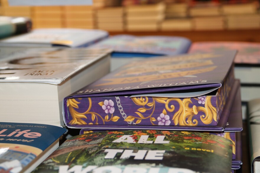 “Mayhem and the Mortal,” by Shanora Williams, is an example of a hardcover book with sprayed edges. The design at the edge of the pages features purple flowers and a gold tree. (Kevin Perez/WUFT News)