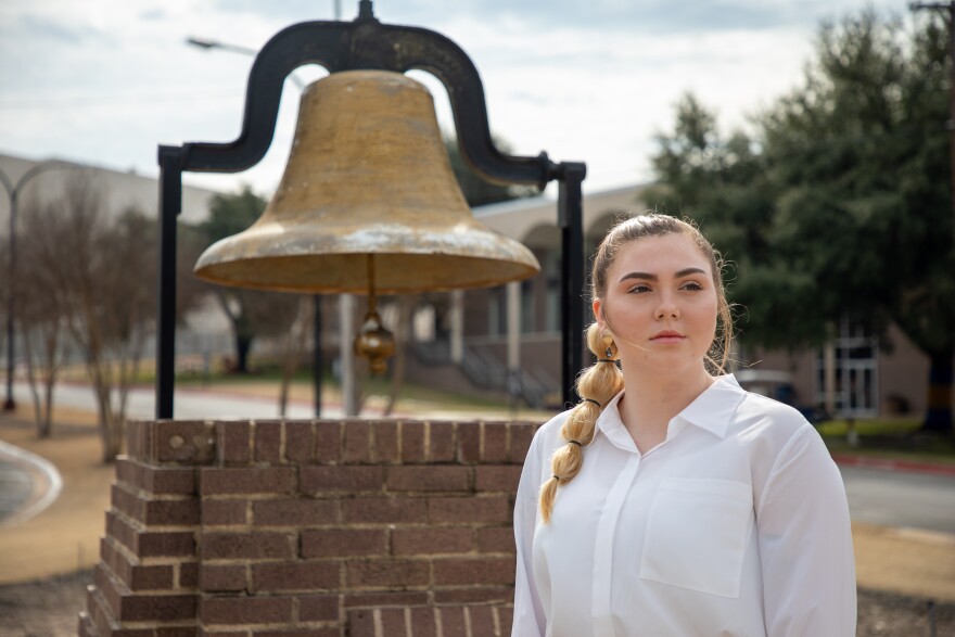 Ellie McCrae standing in front of Paul Quinn's old bell.