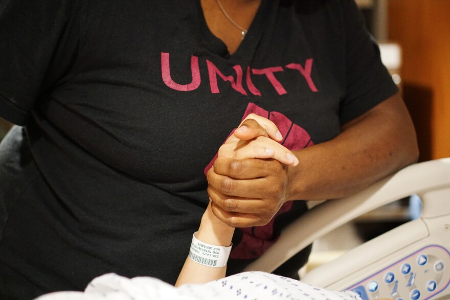 Ms. Tilus holding a mother's hand while working as a doula.
